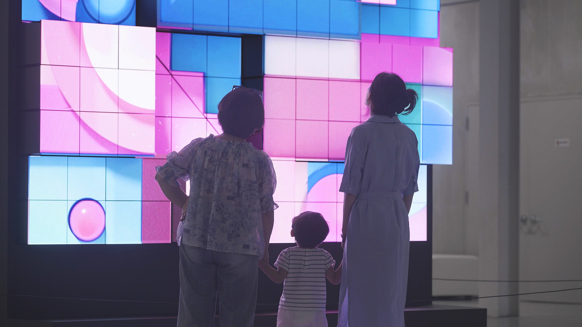 A picture of a child and two adults looking closely at the kinetic LED signage display